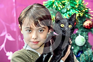 Happy eight year old girl with black cat for Christmas gift