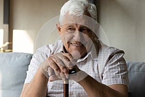 Happy elder 80s man with disability holding knob of cane