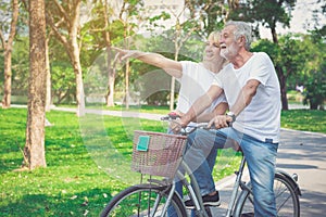 Happy elder couple riding a bicycle in the park