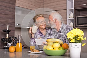 Happy elderly caucasian couple standing behind the kitchen counter