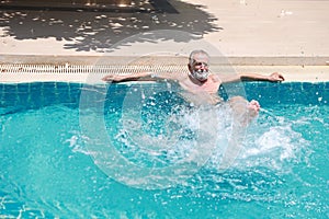 Happy elderly caucasian learn to swim in pool during retirement holiday with relaxation and smiling