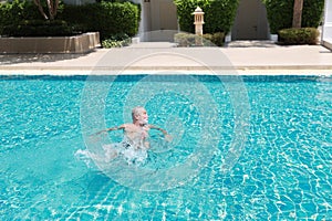 Happy elderly caucasian learn to swim in pool during retirement holiday with relaxation and smiling