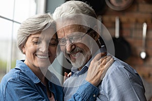 Smiling senior man and woman hug enjoying retirement together