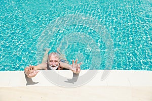 Happy elderly caucasian swimming in pool during retirement holiday with relaxation and smiling