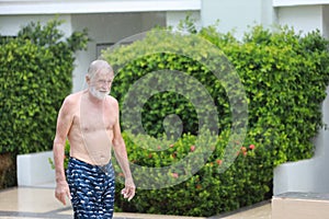 Happy elderly caucasian walking to swimming pool in hotel while raining