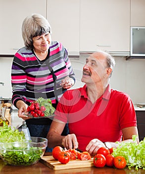 Happy elderly couple cooking lunch in kitchen