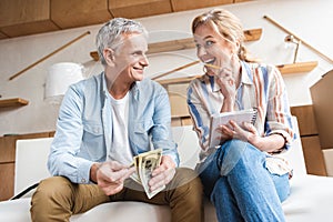 happy elderly couple counting money and laughing while