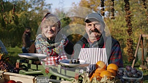 Happy elderly couple of farmers selling products