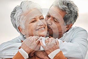 Happy elderly couple, hug and sunset with kiss on cheek, bonding and smile for romance, love and vacation. Senior man