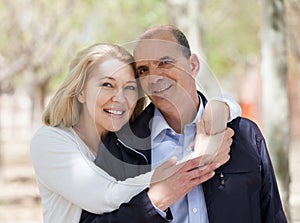 Happy elderly couple hugging in park and smiling