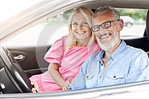 Happy elderly couple, man driving and woman smiling