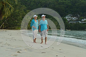 Happy elderly couple resting on a beach. Travel