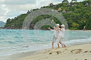 Happy elderly couple resting on beach. Travel