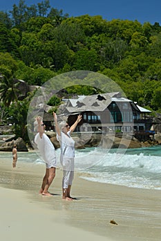 Happy elderly couple resting on beach waving hands