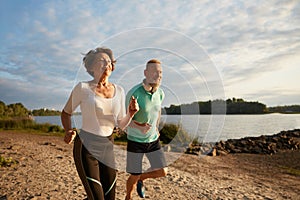 Happy elderly couple running on beach enjoying jogging workout in morning