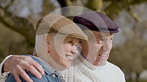 Happy elderly couple spending time in park on sunny autumn day