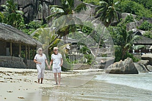 Happy elderly couple walking on tropical beach