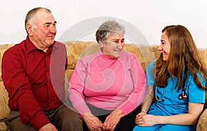 Happy elderly couple and young caregiver