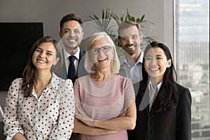 Happy elderly leader woman and colleagues looking at camera