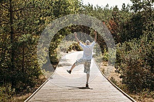 Happy elderly man emotionally expresses his emotions. In the park on the trail