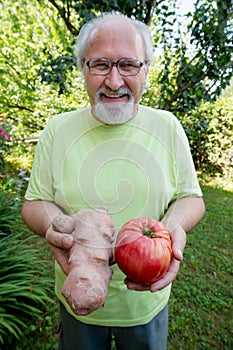 Happy elderly man with potato and tomato