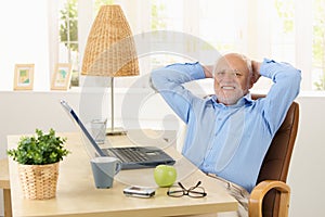 Happy elderly man smiling at desk