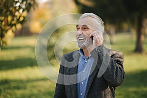 Happy elderly man speak with somebody by the phone. Handsome senior man with beautiful beard smile and rejoice