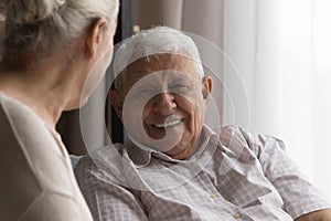 Happy elderly man talking to wife, female carer at home