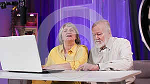 happy elderly man and woman having fun while broadcasting live on social networks and communicating with subscribers