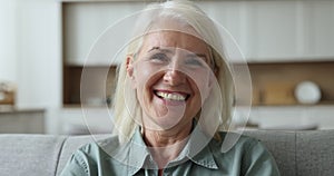 Happy elderly mature lady posing indoors, looking at camera