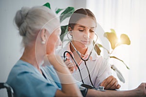 Happy Elderly patient talk with woman doctor at room in hospital. Doctor use stethoscope listening lung of elderly patient.