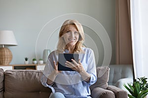 Happy elderly pensioner woman using modern wireless technology at home