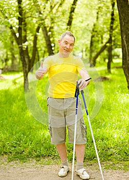 Happy elderly people engaged in Nordic walking and showing thumbs up