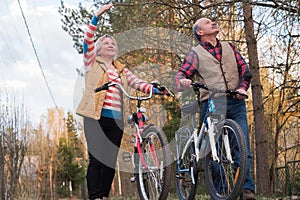 Happy elderly senior couple cycling in park