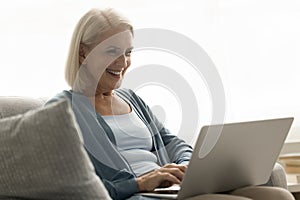 Happy elderly senior freelance woman typing laptop computer