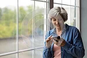 Happy elderly woman have fun using smartphone gadget