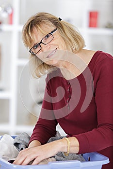 happy elderly woman holding laundry basket