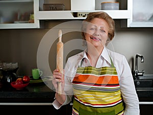 Happy elderly woman in the kitchen holding cooked dumplings and showing thumbs up.