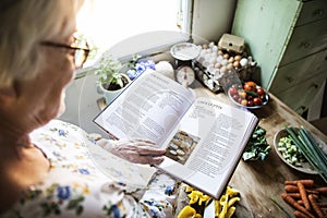 Happy elderly woman reading a cookbook photo