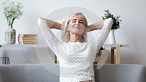 Happy elderly woman relax on sofa at home