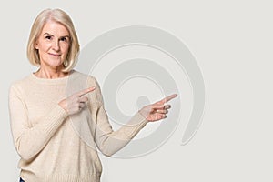Happy elderly woman showing to empty space for copyspace