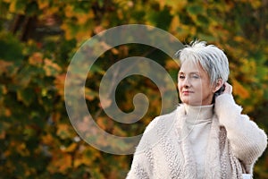 Happy elderly woman touchs her hair in nature