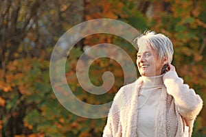 Happy elderly woman touchs her hair in nature