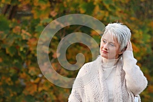 Happy elderly woman touchs her hair in nature