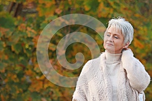 Happy elderly woman touchs her hair in nature