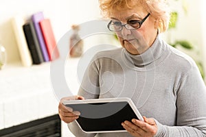 Happy Elderly woman using a tablet and laughing