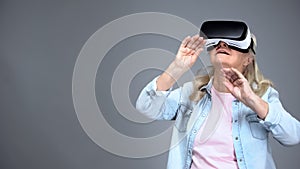 Happy elderly woman wearing VR headset, playing games, innovative technologies