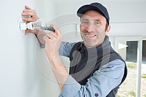 happy electrician at work - installing lamp on wall