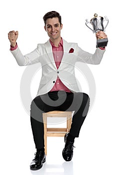 Happy elegant businessman celebrating success by holding a trophy up
