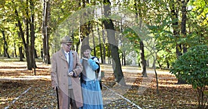 Happy, elegant, elderly married couple walking together in sunny park